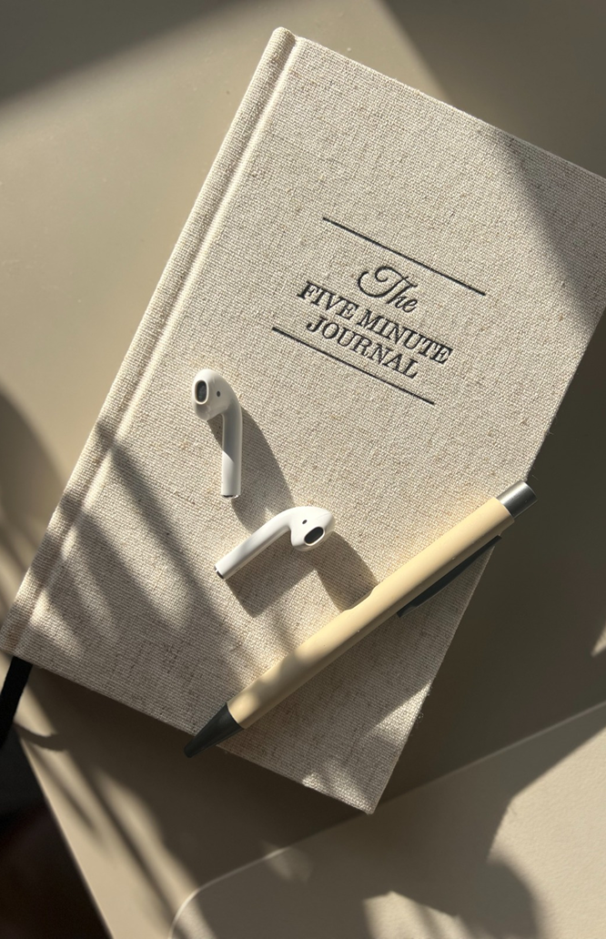 Caderno e caneta sobre uma superfície iluminada, representando planejamento e clareza.